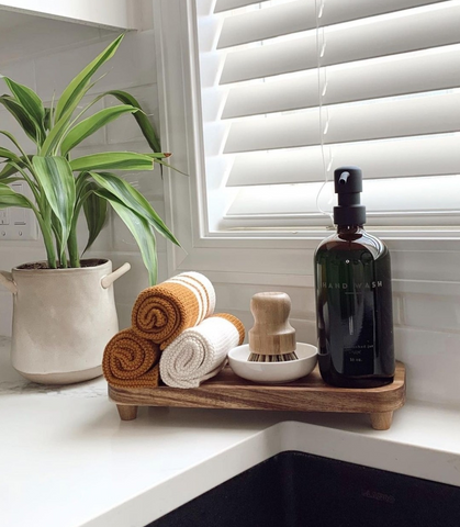 Wooden bathroom tray with soap bottle dispenser, brush and towels