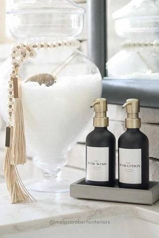 Modern Luxurious White Bathroom Space Decorated With Golden Accessories and Glass Bottle Soap Dispensers