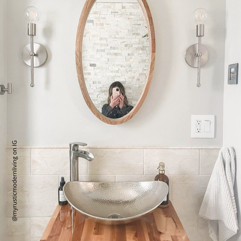 Espejo ovalado sobre fregadero curvo con dispensador de jabón en tarro pulido