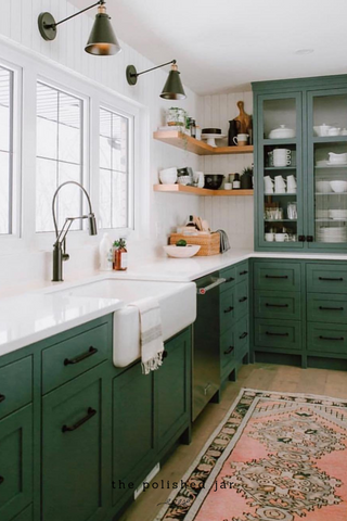 Los dispensadores de jabón en tarro pulido en la encimera de la cocina con gabinetes verdes