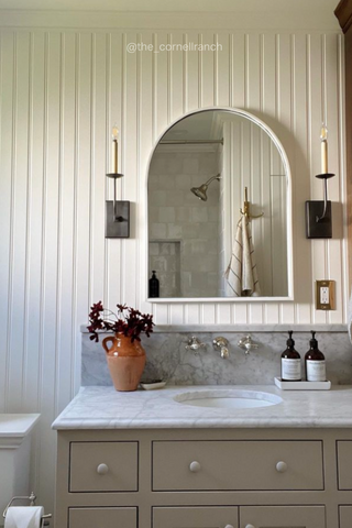 White and brown bathroom with bottle dispensers on counter