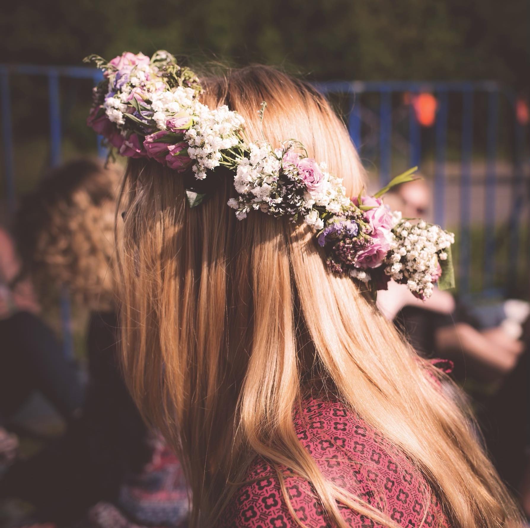 Woman looking away from the camera with a crown of flowers on her head.