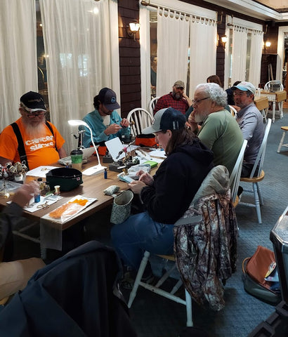 people sitting around a table tying flies