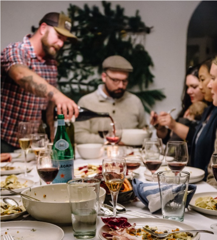 person pouring wine for a dinner party