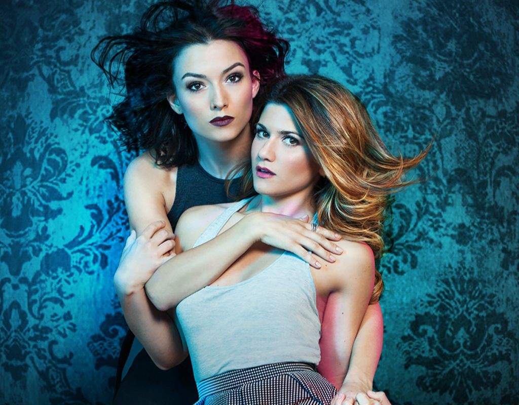 Five years since they vanquished the apocalypse, Laura and Carmilla enlist help from their old friends from Silas University to uncover a supernatural threat tied to Carmilla's past. Laura is shown leaning back on Carmilla.