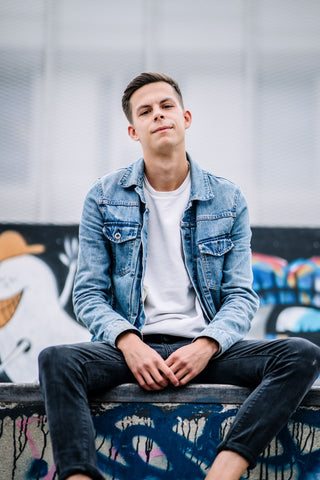 Model wearing a denim jacket with rolled up cuffs along with a pair of dark pants with the ankles rolled up.