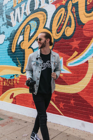 Model wearing a denim jacket with a black shirt underneath along with a pair of dark pants.