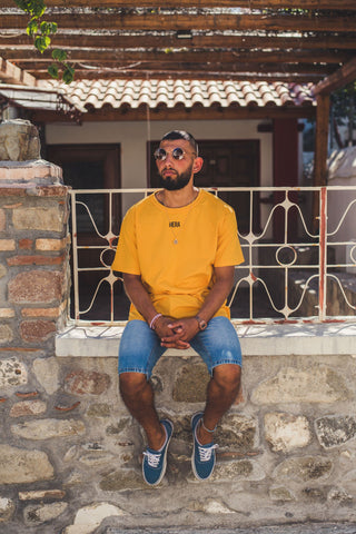 Model wearing a yellow shirt with a pair of cut-off denim shorts.