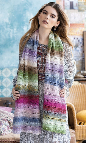 standing woman wearing a long rectangular scarf in soft pastel colors. Striped in festive easter colors of light green, pink, blue and white. the scarf features delicate eyelets every few rows to add a feminine touch