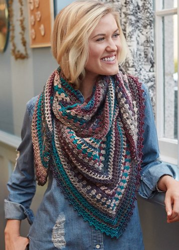 standing blond woman wearing a colorful crocheted cowl in colors of teal purple anf violet