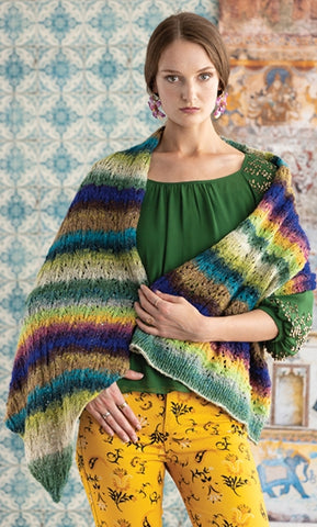 standing woman wearing a colorful striped shawl wrapped around her shoulders. The shawl is in full rainbow colors and offsets her bright yellow pants