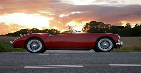 A red sports car glows in the sunset.