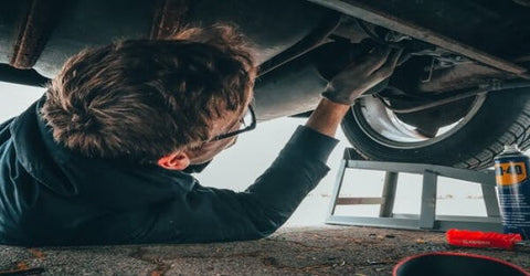 A man lying under the car repairing the car