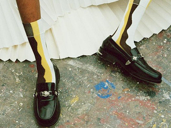 Close up photo of a model wearing black Toga Pulla loafers.