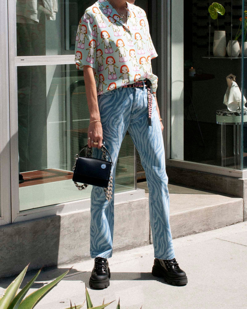 Model wears a printed short sleeve button up and zebra print jeans.