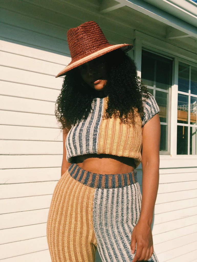 Model wears a brown wide brim hat with a matching two tone yellow and blue striped knit set.