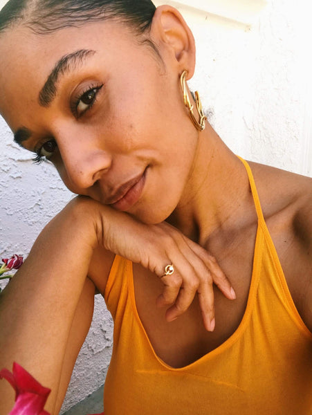 Close up of Courtney wearing an orange halter top and gold jewelry. 