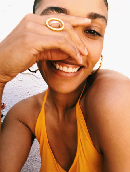 Close up of Courtney wearing an orange halter top and gold jewelry. 