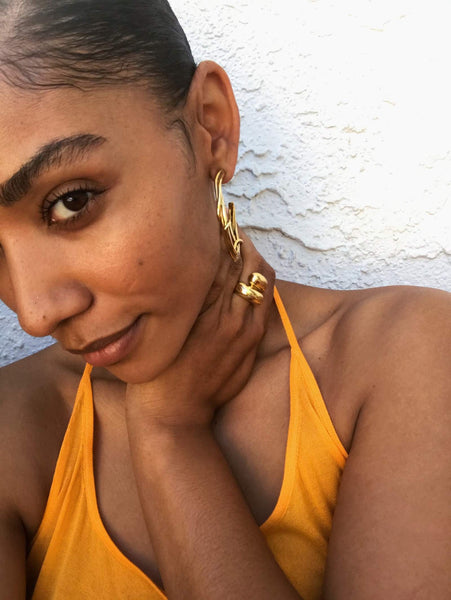 Close up of Courtney wearing an orange halter top and gold jewelry. 