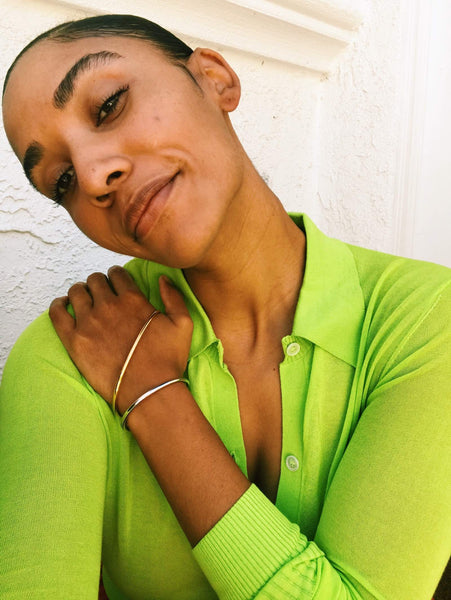 Close up of Courtney wearing an green cardigan top and two tone bracelet. 