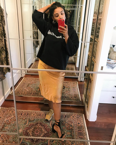 Courtney takes a mirror selfie wearing a black cropped hoodie over a nude slip dress.