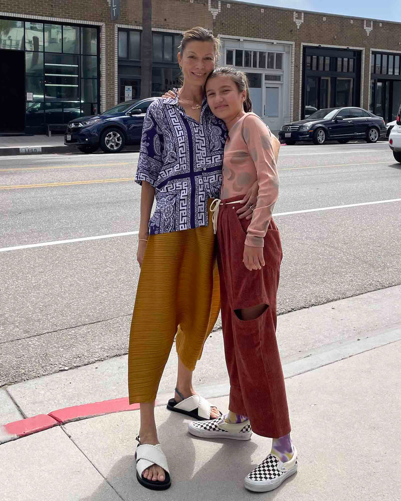 Mother and daughter stand on the sidewalk. 