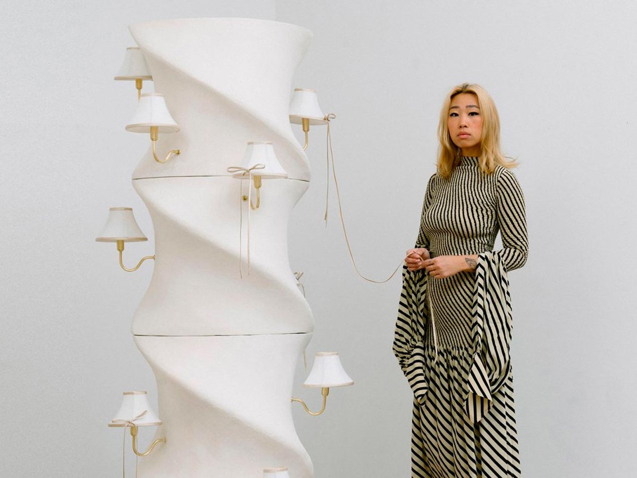 Furniture designer Eny Lee Parker standing next to a large lighting sculpture.