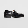 Side photo of a black leather loafer with rubber soles.