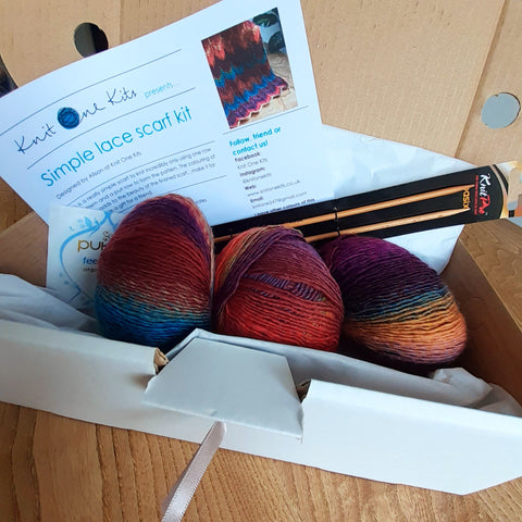 Box showing 3 balls of multi coloured yarn, pair of needles, printed pattern