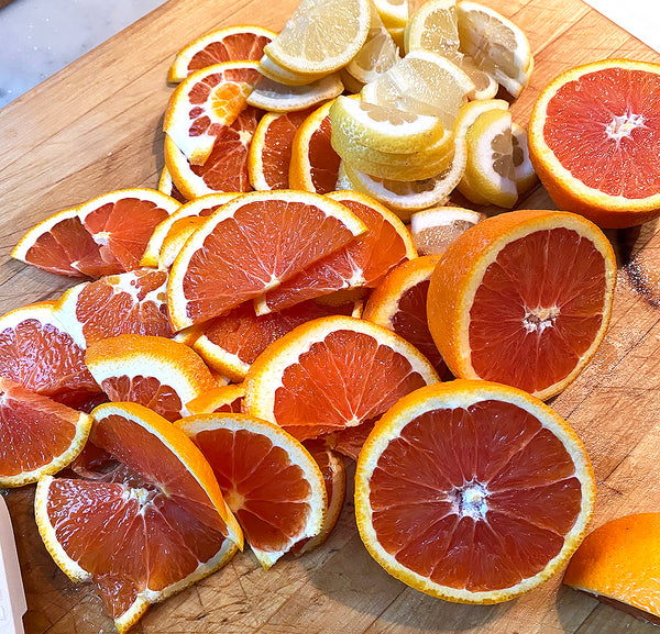 Sliced oranges and lemons on a wood board.