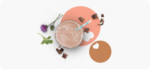 A glass of Milkflow chocolate with a straw in it appears next to chocolate shavings and herbs