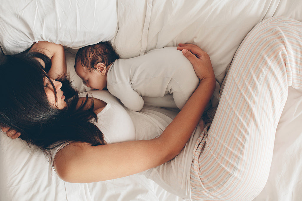 Mother cuddling with her baby on the bed.