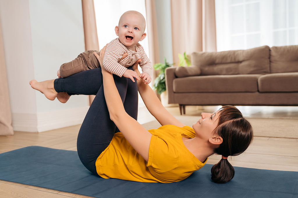 mother on yoga mat lifting baby in the air