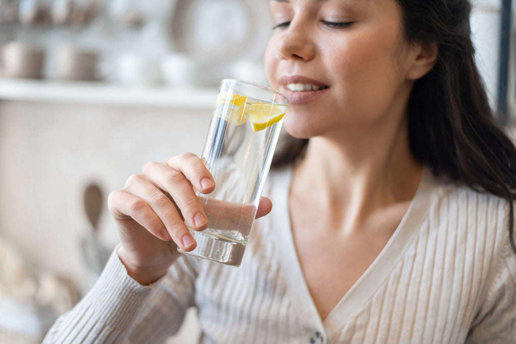 Woman drinking lemon water out of a glass