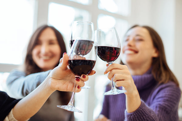 Women cheers red wine glasses