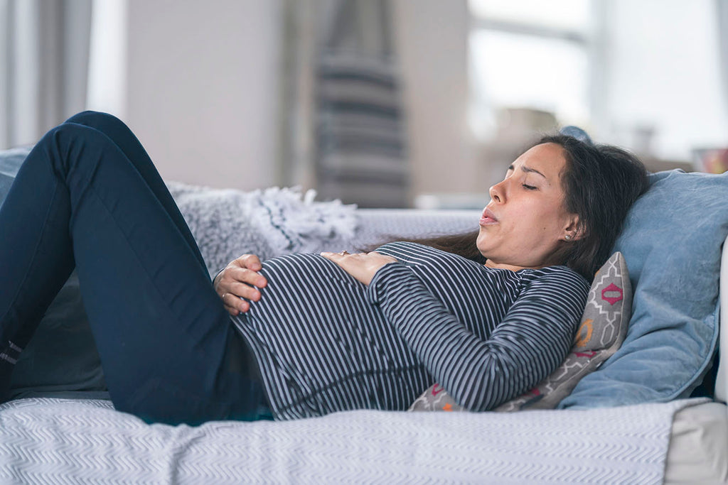 pregnant woman on couch experiencing nausea