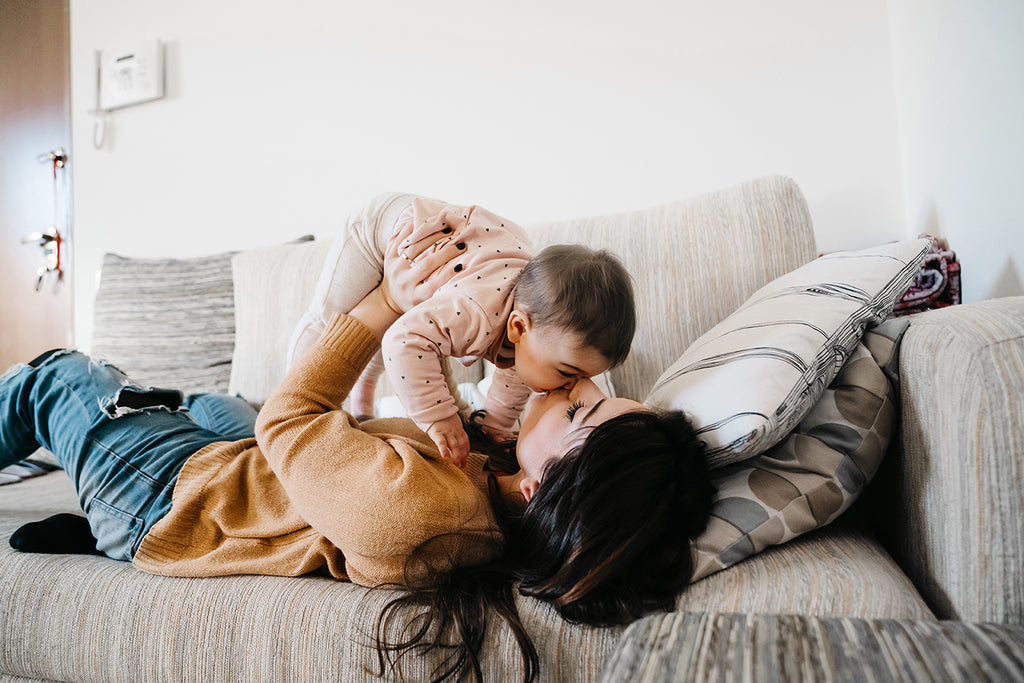 Mother playing with baby on couch