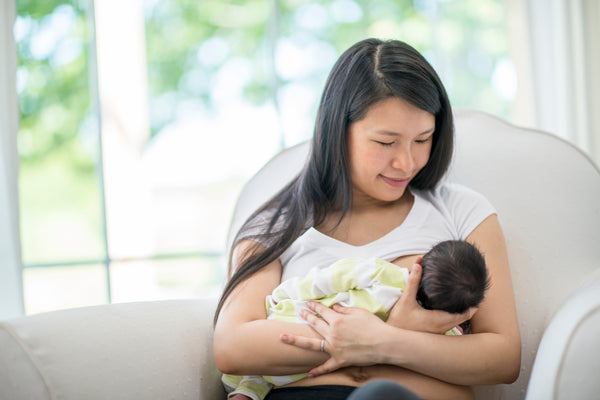 A woman cradles her baby as she breastfeeds