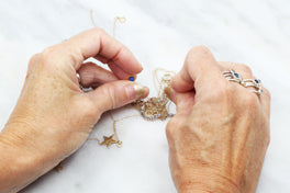 Hands untangling knotted chains with pins