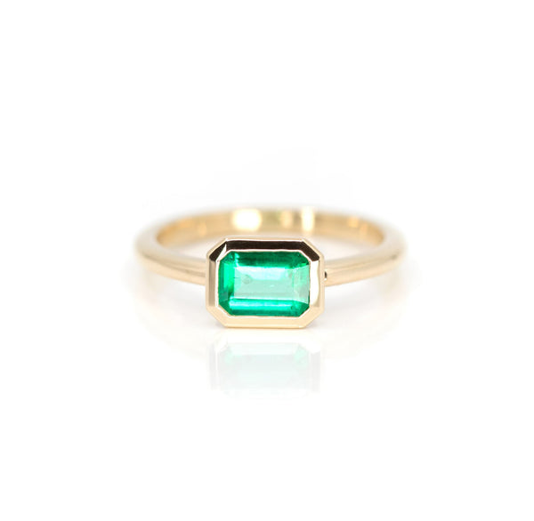 front view of bezel setting emerald gemstone yellow gold bridal custom made engagement ring on white background