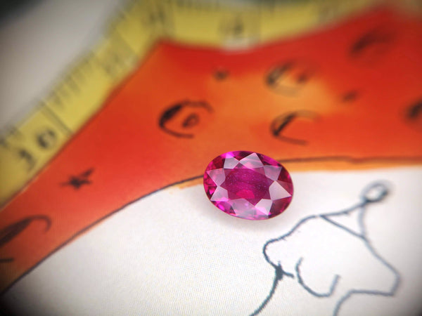 montreal gemstone broker bena jewelry designer oval shape ruby pinkish red gem on orange and white background