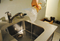 Person pouring water out of the Chemex in a sink