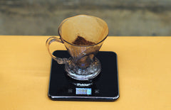 ground coffee inside clever, being weighed on a scale