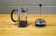 Pot with ground coffee sitting next to the press