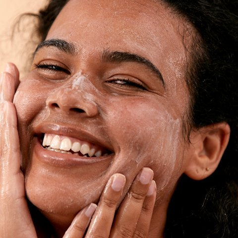woman exfoliating face and smiling