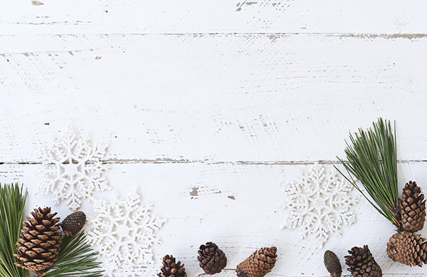 A white painted wooden table with pinecones, snow flakes and twigs on top