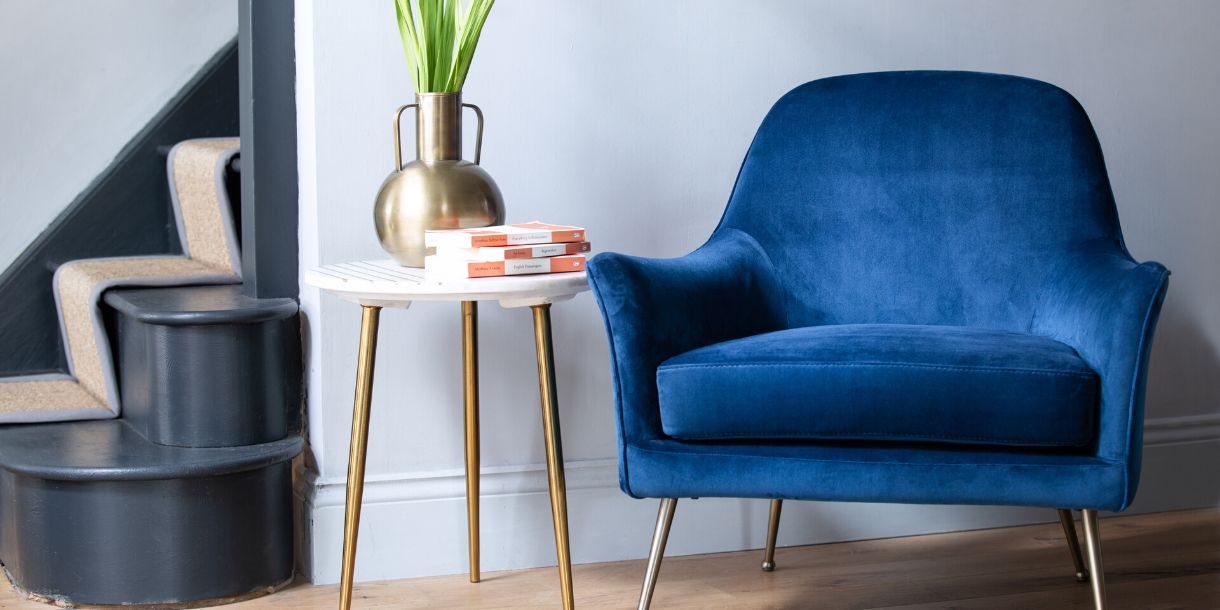 Blue velvet armchair with side table and grey painted stairs