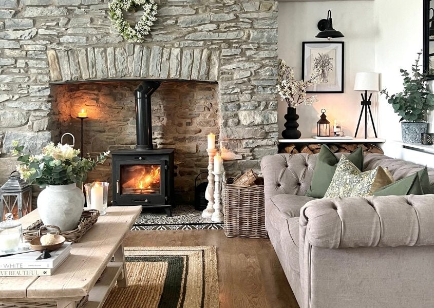 fabric chesterfield sofa next to open fireplace with wood burner