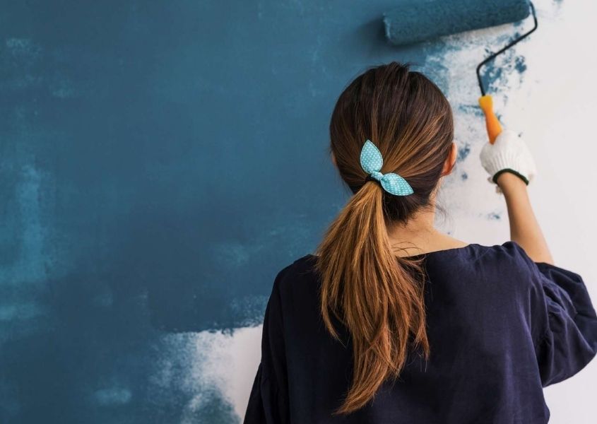 Woman painting a wall for quick ways to transform your room over a weekend blog