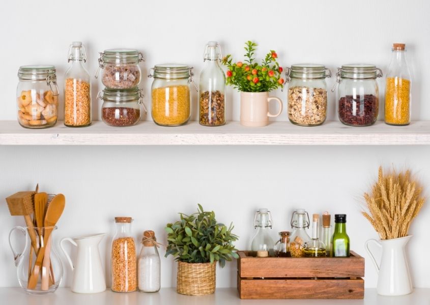 open wooden shelves with glass jars and plants